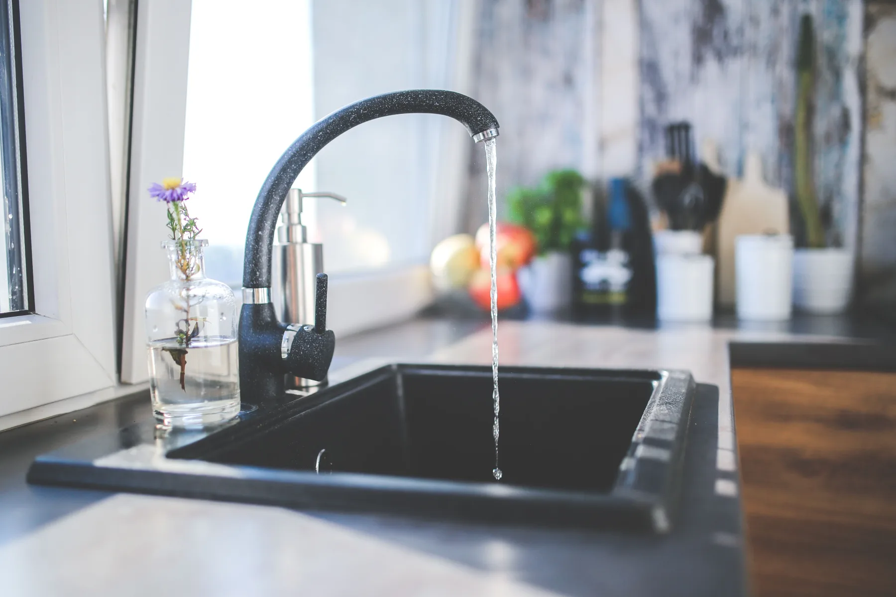 Clear water flowing from a kitchen faucet into a drinking glass